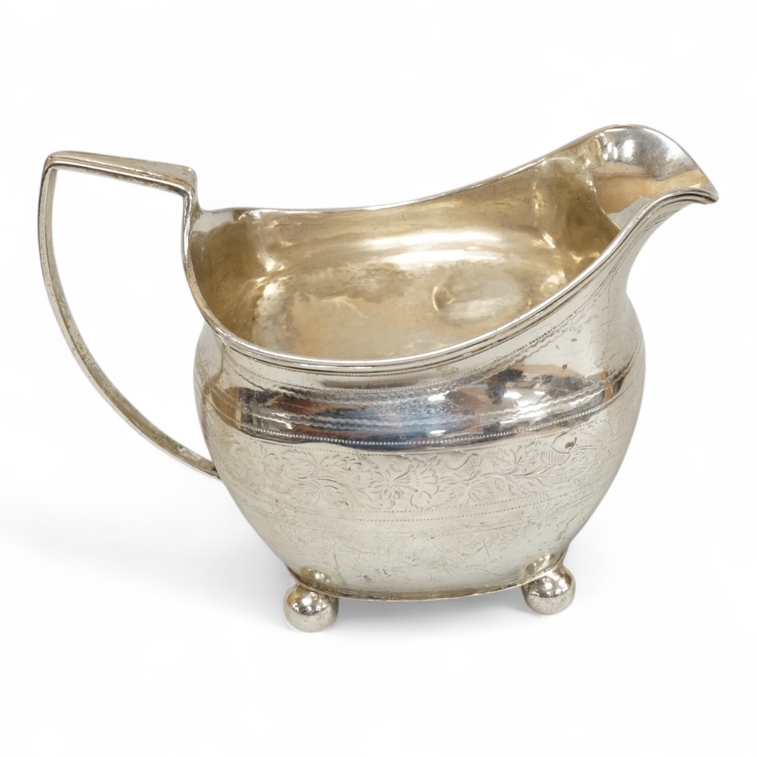 A George III silver cream jug, on four ball feet, London, 1812, 95mm, with engraved foliate band, maker's mark rubbed.